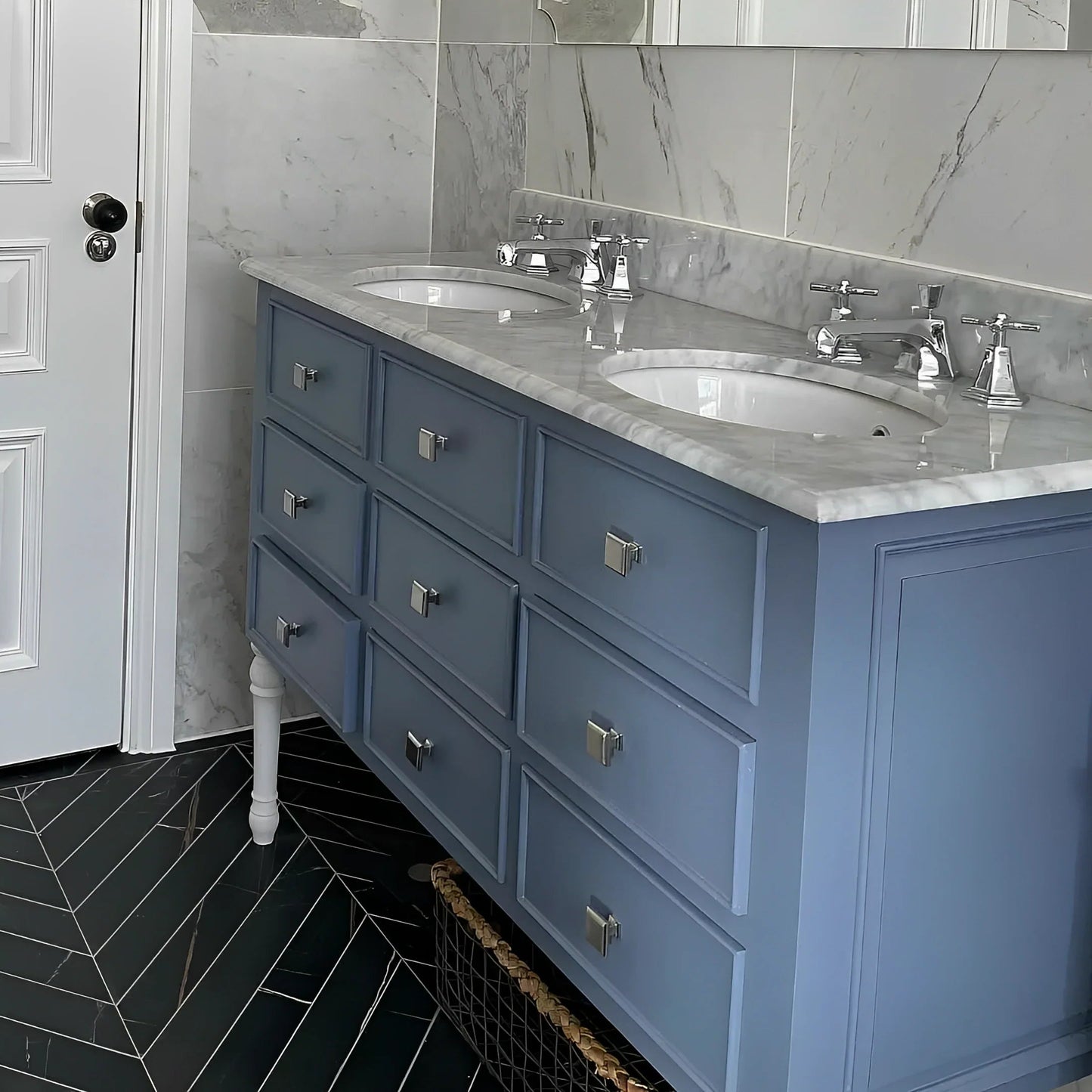 Bathroom with blue vanity, marble countertop, and black tiled floor.