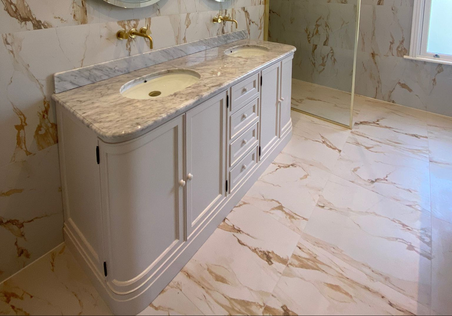 Bathroom vanity with marble countertop and floor in a marble-patterned room.