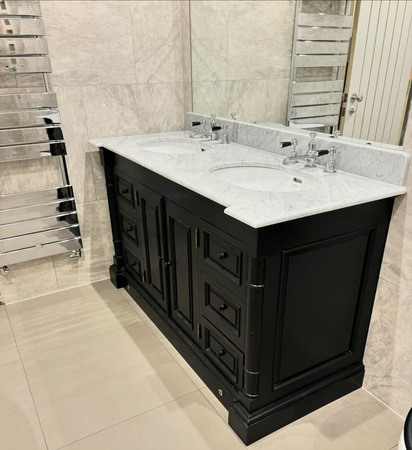 Bathroom vanity with marble countertop and sink in a tiled bathroom.