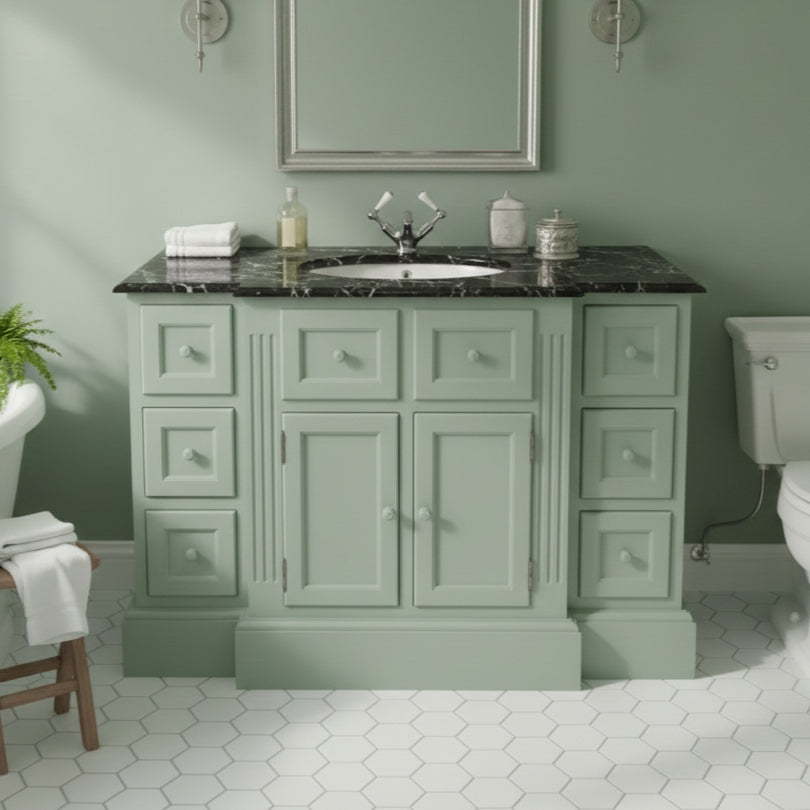 Bathroom vanity with black countertop and mirror in a green bathroom.