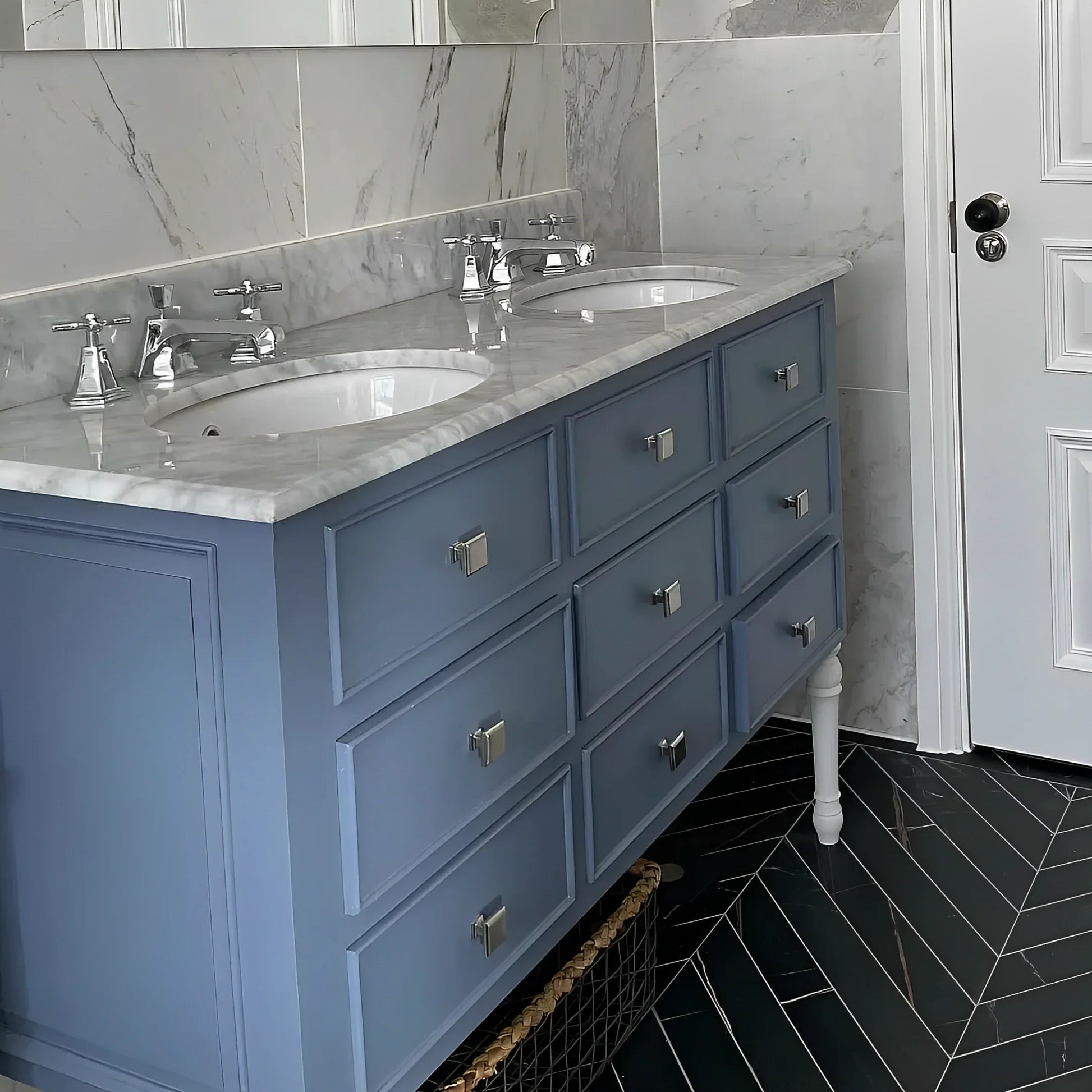Bathroom with blue vanity, marble countertop, and black tiled floor.