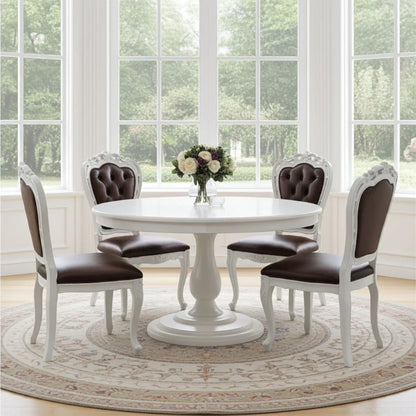 Dining room with a round white table and four matching chairs with brown cushions, in front of large windows.