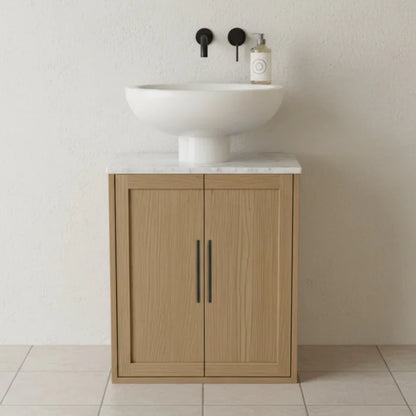 Wooden vanity with white sink and marble countertop against a plain wall.
