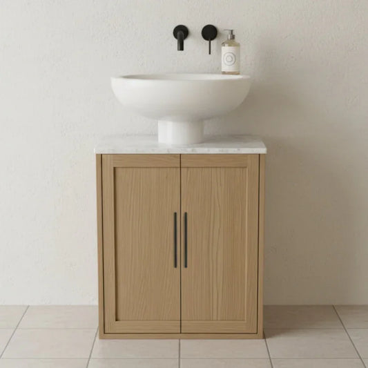 Wooden vanity with white sink and marble countertop against a plain wall.