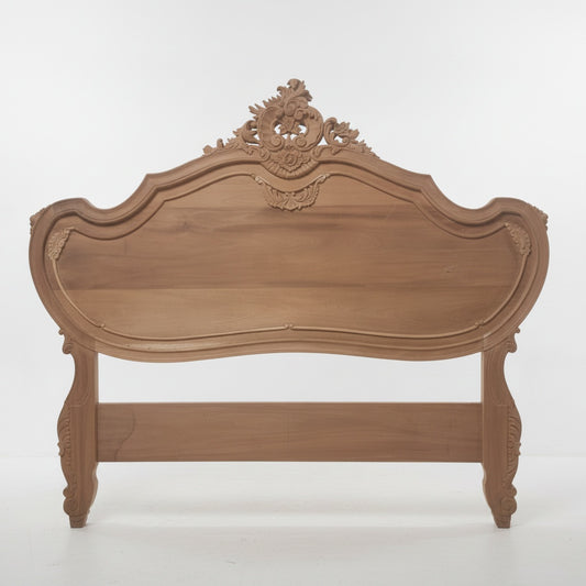 An ornate wooden headboard with a curved, baroque-style design, featuring intricate floral carvings at the top and decorative legs, shown against a plain white background.