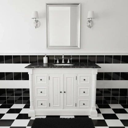 Bathroom with white vanity, black countertop, and black and white tiled floor.