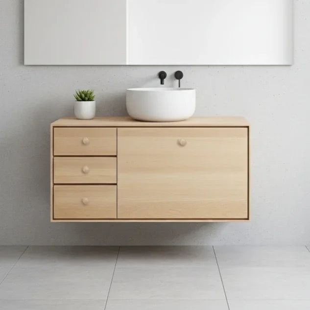 Bathroom vanity with wooden cabinet, white sink, and decorative elements on a light gray wall.