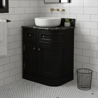Bathroom with black vanity unit, white sink, and tiled walls.