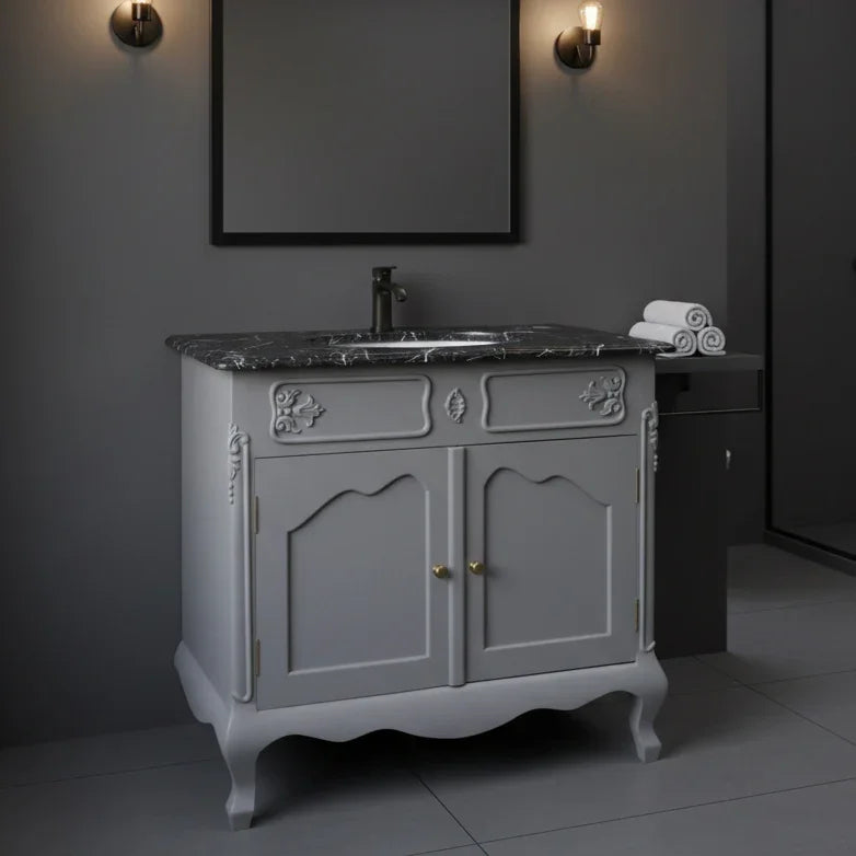 Gray bathroom vanity with marble countertop and mirror in a dimly lit room.
