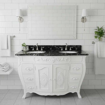White bathroom vanity with black marble top against a tiled wall.