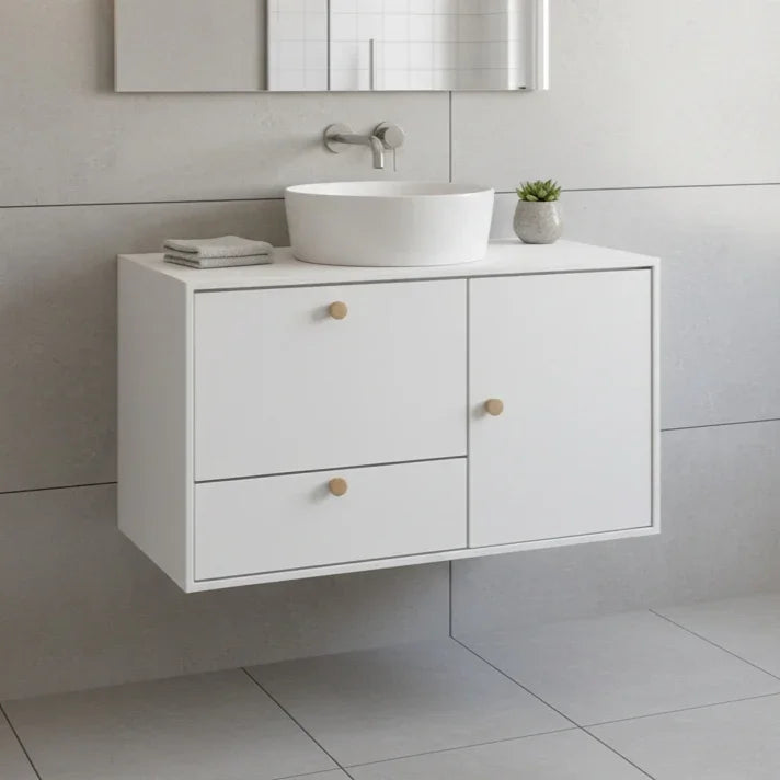 Bathroom vanity with white sink and drawers against a tiled wall.