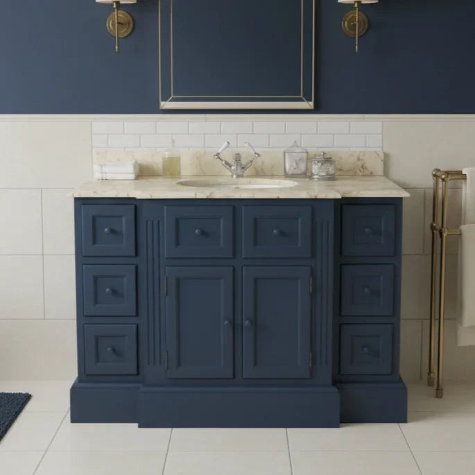 Navy blue bathroom vanity with marble countertop against a blue wall.