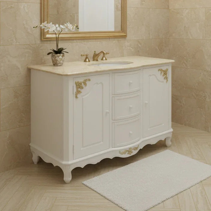 Bathroom vanity with marble countertop and gold fixtures against beige tiled walls.