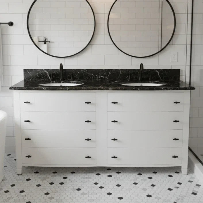 Bathroom vanity with black marble countertop and round mirrors on a tiled wall.