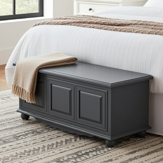 Gray storage bench with a blanket in front of a bed in a bedroom.