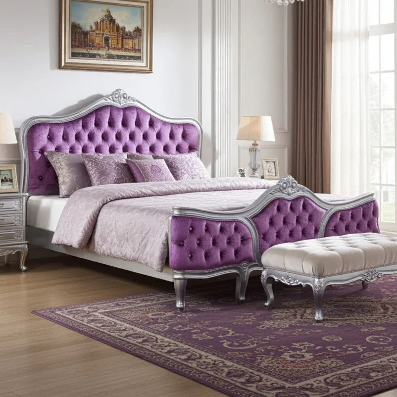 Luxurious bedroom with a purple and silver bed and matching ottoman.