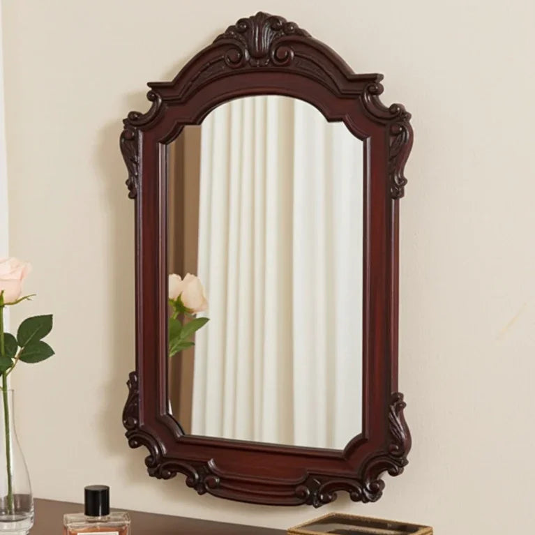 Decorative wall mirror with a wooden frame on a beige wall.