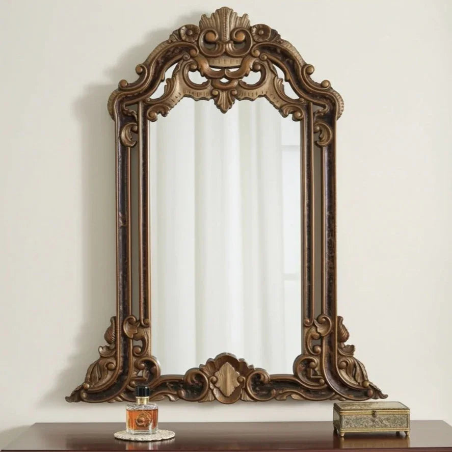 Decorative wooden mirror with intricate carvings on a white wall.