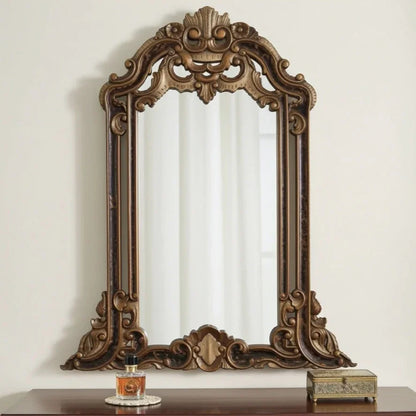 Decorative wooden mirror with intricate carvings on a white wall.