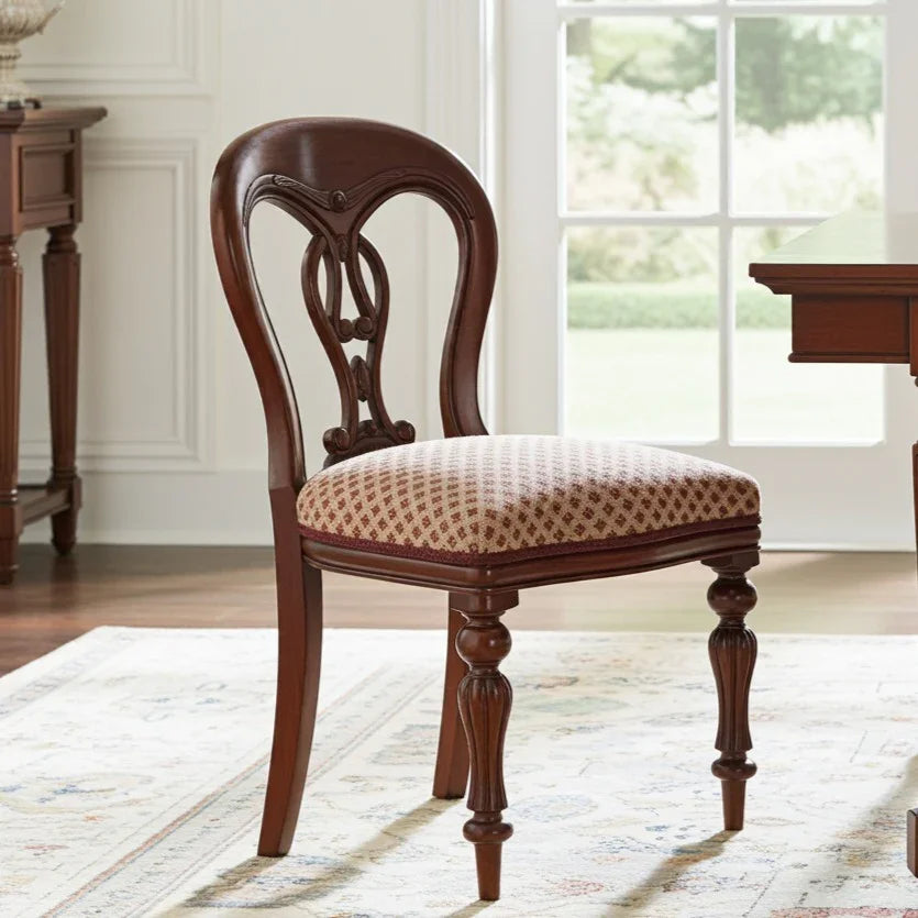 Wooden chair with patterned cushion in a room with a window and desk.