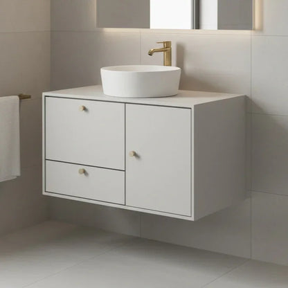 Bathroom vanity with white sink and gold faucet against a tiled wall.