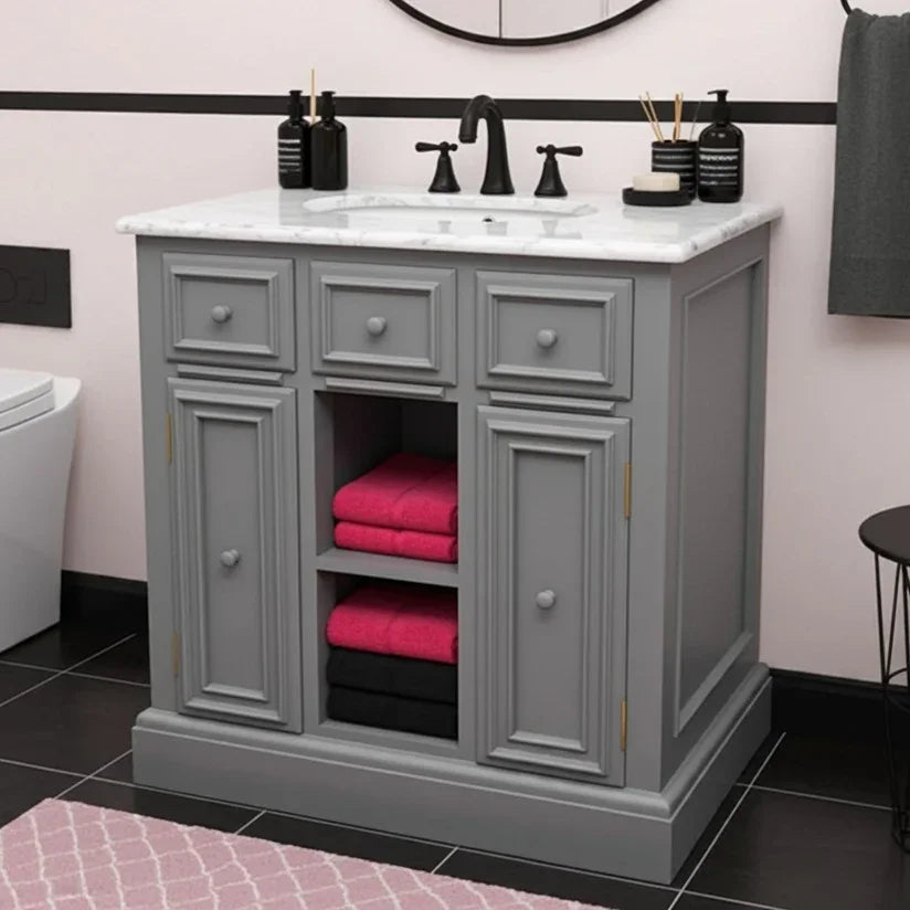 Gray bathroom vanity with open cabinet showing pink and black towels, against a light pink wall.