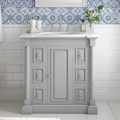 Gray bathroom vanity with white countertop against a tiled wall with blue and white pattern.