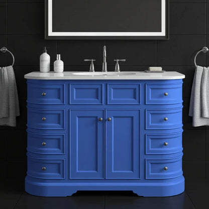 Blue bathroom vanity with white countertop, sink, and fixtures against a black tiled wall.