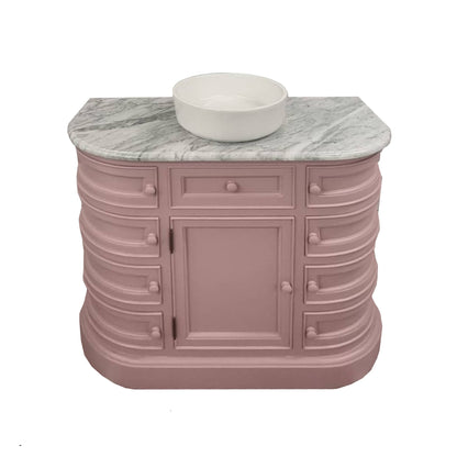 Pink bathroom vanity with marble countertop and white basin on a white background