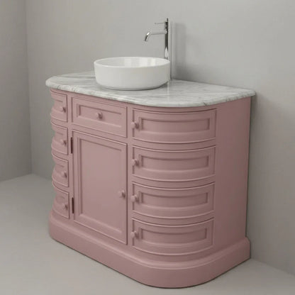 Pink bathroom vanity with white sink and marble countertop against a gray wall.
