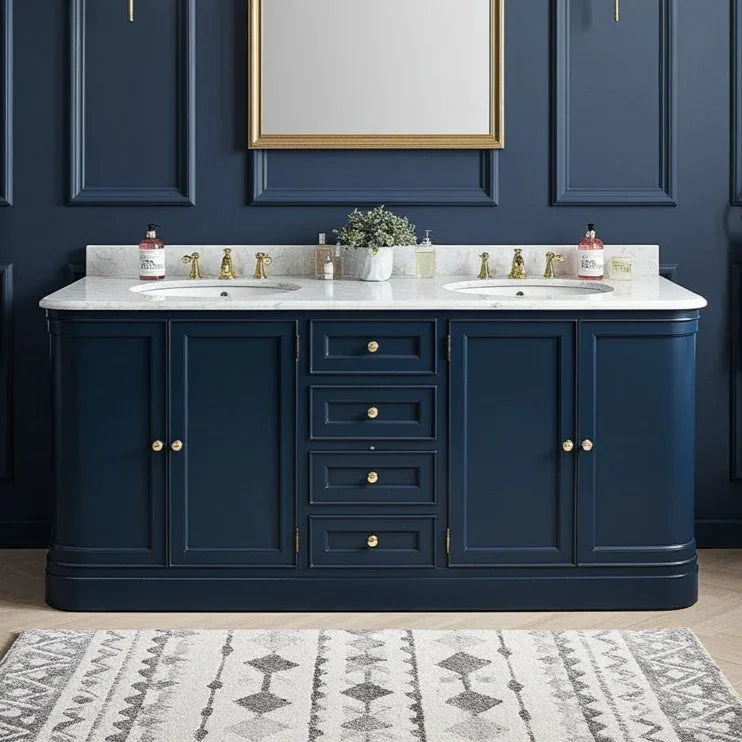 Bathroom vanity with marble countertop, blue cabinets, and gold fixtures against a dark blue wall.