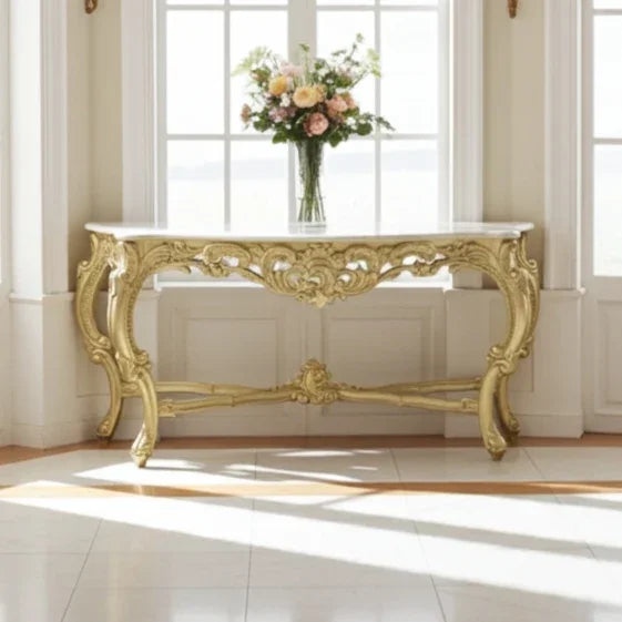 Decorative gold console table with a vase of flowers in a bright room.