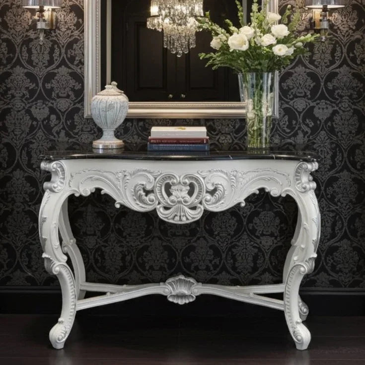 Decorative console table with ornate design against a black patterned wall.