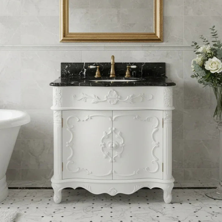 White bathroom vanity with black marble top and gold fixtures, featuring a decorative mirror.