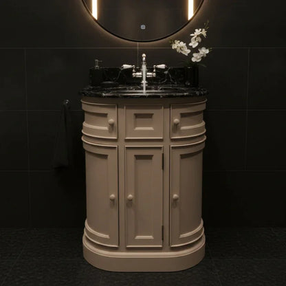 Beige bathroom vanity with black countertop and round mirror in a dark tiled room