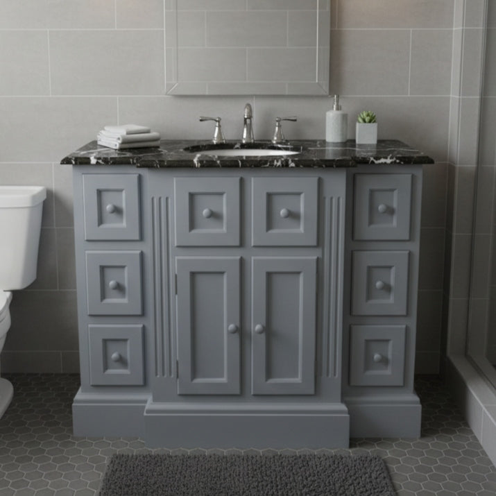 Gray bathroom vanity with black countertop and sink in a tiled bathroom.