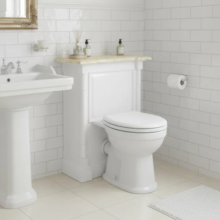 Bathroom with white toilet and sink against a tiled wall.