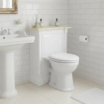 Bathroom with white toilet and sink against a tiled wall.