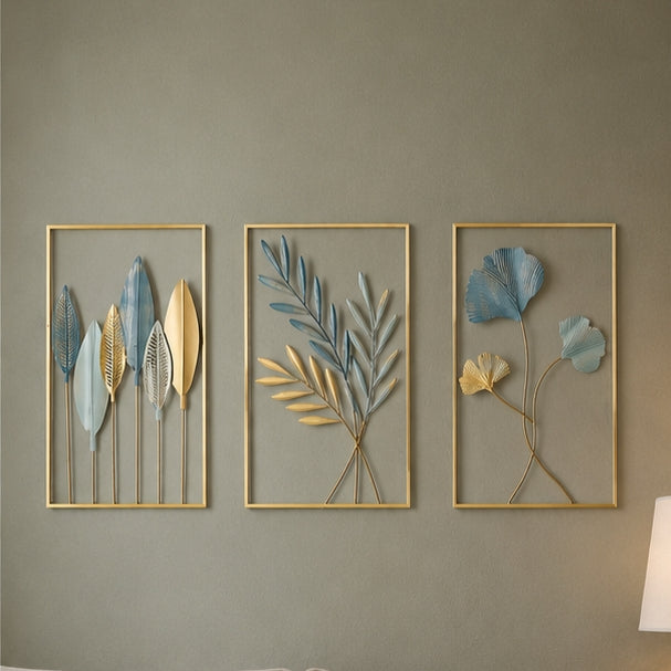 Three framed wall art pieces with leaf designs on a gray wall.