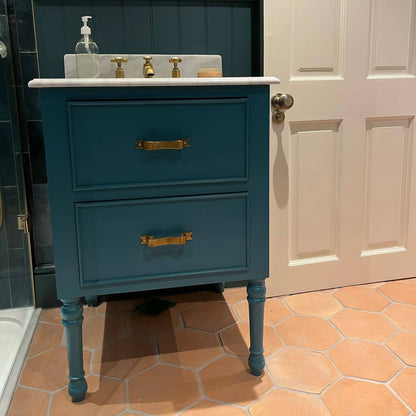 Blue vanity with gold handles in a bathroom setting