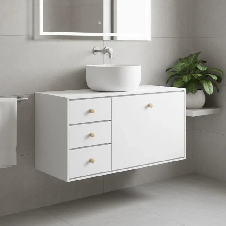 Bathroom vanity with white sink and drawers, illuminated mirror, and plant.